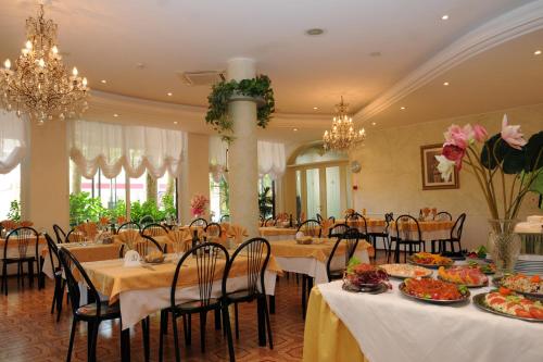 a dining room with tables and chairs and chandeliers at Hotel Flora in Bellaria-Igea Marina