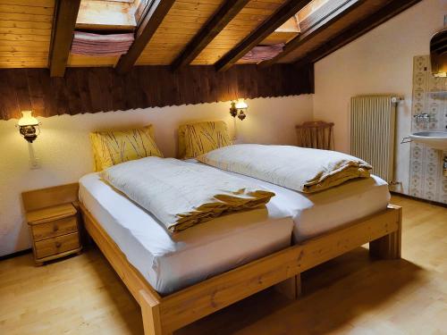 Cama grande en habitación con techo de madera en Apartments Atlas, en Saas-Grund