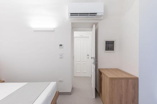a white bedroom with a bed and a wooden cabinet at Dimora dei Celestini in Manfredonia