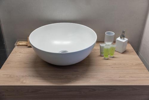 a white bowl on a wooden counter with two glasses at Dimora dei Celestini in Manfredonia