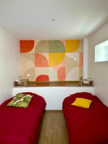 twee bedden in een kamer met een schilderij aan de muur bij Charmant et chaleureux gîte dans le vignoble in Sigolsheim