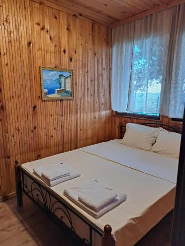 uma cama num quarto de madeira com uma janela em Комплекс Джулай Морнинг em Kiten