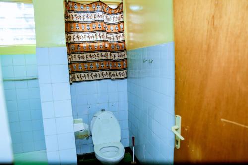 a bathroom stall with a toilet and a curtain at INZOZI AFRICA HOUSE B&B-Kimihurura in Kigali