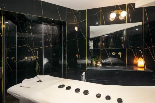 a black bathroom with a tub and a mirror at Pool, Sauna, Gym & Spa @ Beach-Front Apartment Hotel in Ashqelon