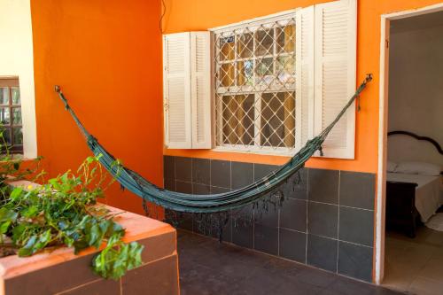 a hammock in a room with an orange wall at Pousada Chácara Maria da Graça in Tremembé