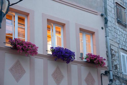 a white building with purple flowers in windows at Apartments Allegra in Sinj