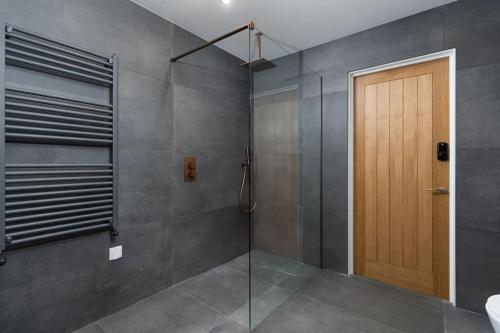 a bathroom with a shower and a wooden door at Stunning new 1 bed apartment in Marazion. in Marazion