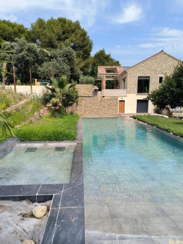 a swimming pool in front of a house at Mas L'Escale des Dentelles in Aubignan