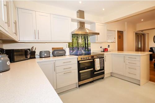 Bramall House Accommodation في Fewston: مطبخ بدولاب بيضاء وفرن علوي موقد
