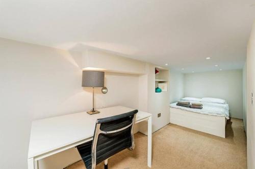 a white desk with a lamp and a bed in a room at Flat w/ terrace in Notting Hill in London