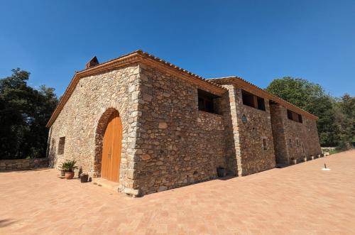 a brick building with an orange door on a brick road at Can Carreres - Un lloc on desconnectar en família in El Pasteral