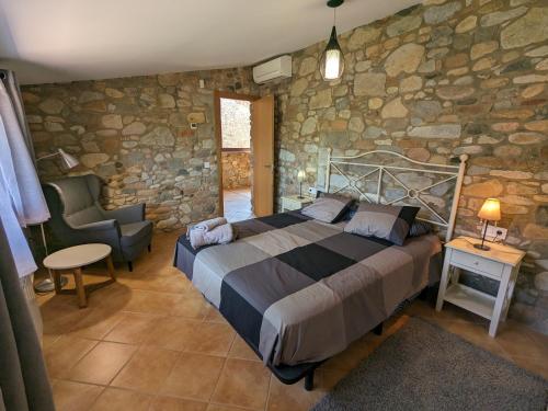 1 dormitorio con cama y pared de piedra en Can Carreres - Un lloc on desconnectar en família, en El Pasteral