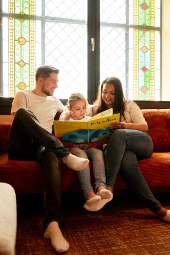 a group of three people sitting on a couch reading a box at Heavens Hotel in Hoorn