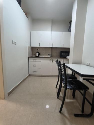 a kitchen with white cabinets and a table and chairs at דירה במרכז in Bene Beraq