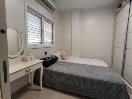 małą sypialnię z łóżkiem i lustrem w obiekcie דירה במרכז w mieście Bene Beraq