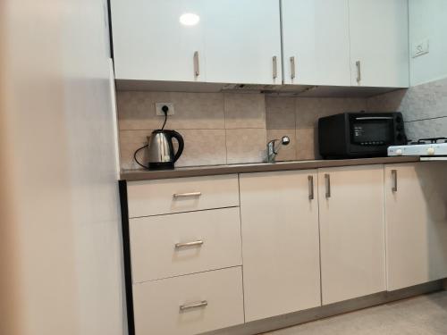 kuchnia z białymi szafkami, zlewem i kuchenką mikrofalową w obiekcie דירה במרכז w mieście Bene Beraq