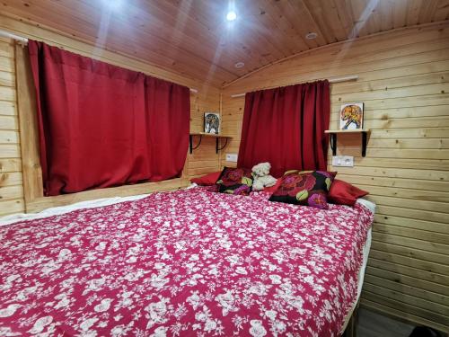 1 dormitorio con 1 cama grande con manta roja en La Roulotte du Cagire - 4 pers - Pyrénées en Villeneuve-de-Rivière