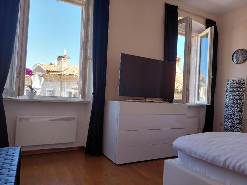a bedroom with a tv on a dresser with two windows at App OLIVE Old Town in Poreč