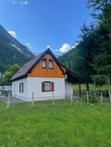 une maison dans un champ avec des montagnes en arrière-plan dans l'établissement Juliana Cottage, à Vallée de la Soča