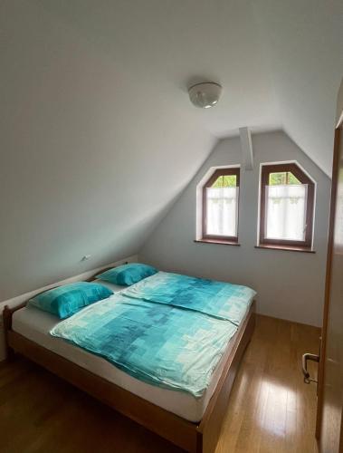 a bedroom with a bed with blue sheets and two windows at Juliana Cottage in Soča