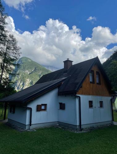 une maison blanche avec un toit en bois dans l'établissement Juliana Cottage, à Vallée de la Soča