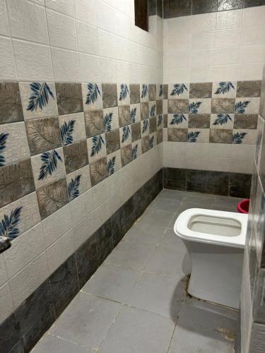 a bathroom with a toilet and a tiled wall at HOTEL DIVYA in Rishīkesh