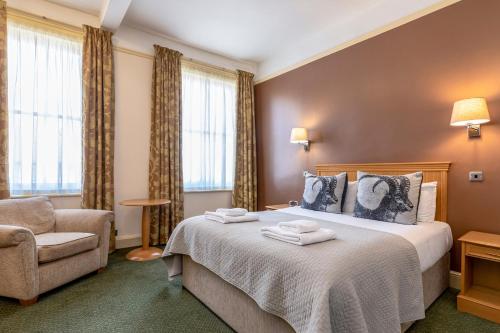 a hotel room with a bed and a chair at Swan Revived Hotel in Milton Keynes