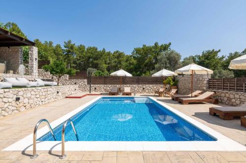 a pool in a backyard with a stone wall at Adonis Villa in nature in Ixia