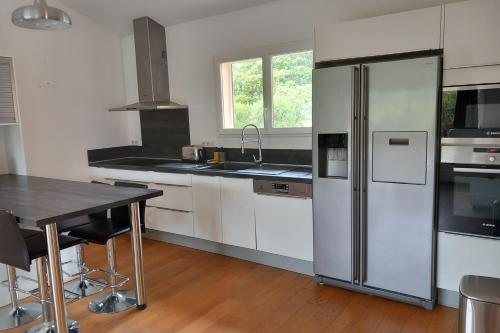 une cuisine avec un réfrigérateur en acier inoxydable et une table dans l'établissement Cosy cocoon with balcony close to the sea, à Porto-Vecchio