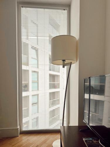 a desk with a lamp in front of a large window at Canary Wharf - Luxury Apartments in London