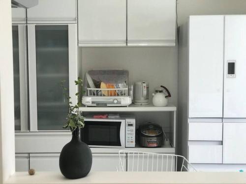 a kitchen with a vase on a counter with a microwave at 空港まで車で15分〜ビーチまで徒歩1分〜海沿いの野鶴居 in Maezato