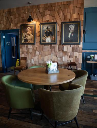 a dining room with a wooden table and green chairs at Loch Lomond Hotel in Balloch