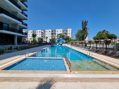 a large swimming pool with chairs and a building at Uğur Apart Sea View in Erdemli