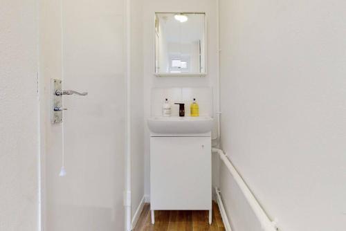 a white bathroom with a sink and a mirror at Modernistic 4 BR house with a garden in Islington in London