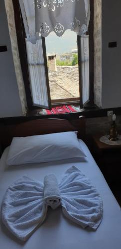 a blue bow tie on a bed with a window at Silver Hill Guesthouse in Gjirokastër