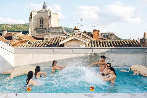 un groupe de personnes dans une piscine dans l'établissement Urban Style LES FLEURINES, à Villefranche-de-Rouergue