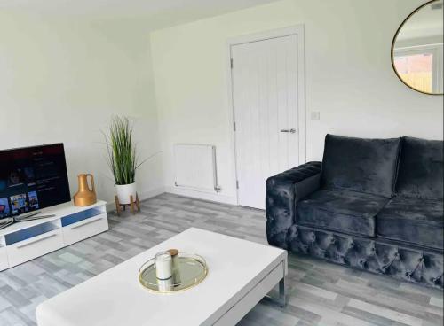 ein Wohnzimmer mit einem schwarzen Sofa und einem Couchtisch in der Unterkunft Luxurious new built kingsize bedroom in Manchester