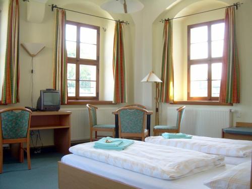 a hotel room with two beds and a desk and windows at Burg Hohnstein in Hohnstein