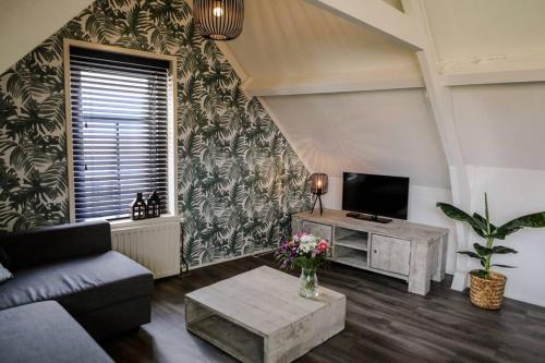 a living room with a couch and a tv at Appartement ‘t-Yesenaertje in Yerseke
