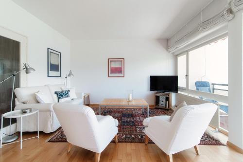 sala de estar blanca con sillas blancas y TV en Aldesago City View by Quokka 360 - flat with a breathtaking view, en Viganello