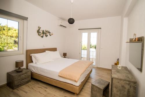 een witte slaapkamer met een bed en een raam bij Villa Zou in Ambelas