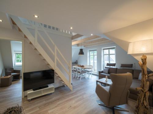 a living room with a couch and a tv and a staircase at Inselsünn Spiekeroog in Spiekeroog