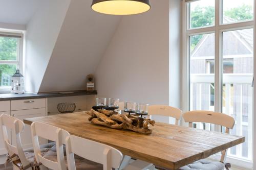 a dining room with a wooden table and chairs at Inselsünn Hotel und Apartments in Spiekeroog