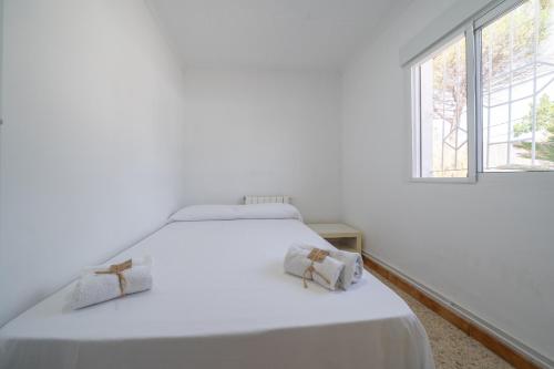 Una cama blanca en una habitación blanca con 2 almohadas. en HomeHolidaysRentals Adaggio - Costa Barcelona, en Fogars de la Selva