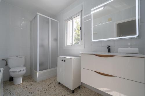Baño blanco con aseo y lavamanos en HomeHolidaysRentals Adaggio - Costa Barcelona, en Fogars de la Selva