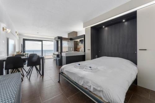 een slaapkamer met een bed en een tafel en stoelen bij DilemmaSea - App met zeezicht, terras én zwembad in Middelkerke