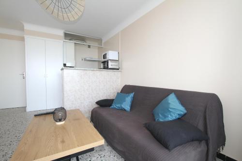 - un salon avec un canapé marron et des oreillers bleus dans l'établissement appartement 2 pieces avec parking et vue sur la marina, à Canet