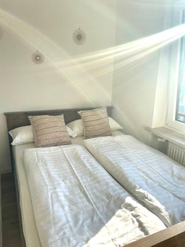 - un lit avec des draps et des oreillers blancs à côté d'une fenêtre dans l'établissement Stilvolle Wohnung im Herzen von Immenstadt - Nähe Mittag, Iller, Inselsee, à Immenstadt