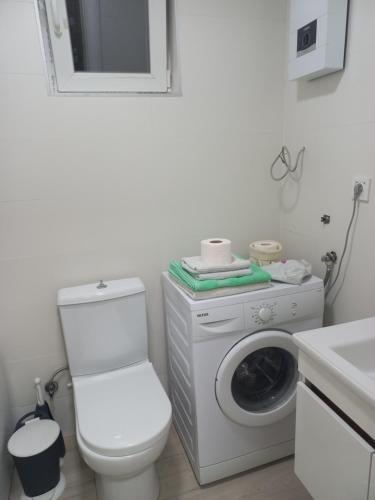 La salle de bains blanche est pourvue de toilettes et d'un lave-linge. dans l'établissement Studio close to town centar, à Skopje