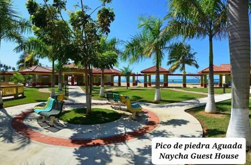 a park with benches and palm trees in front of a resort at La Familia #1 in Aguada